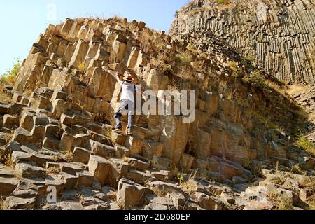 Il viaggiatore arrampica sulle incredibili formazioni di colonne basaltiche conosciute come Sinfonia delle pietre lungo la Gola di Garni, Armenia Foto Stock