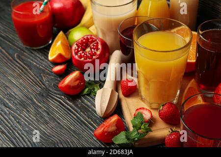 Diversi succhi in bicchieri e barattoli su un tavolo di legno, un set colorato di succhi freschi con barattoli di vetro per un design di bevande salutari Foto Stock