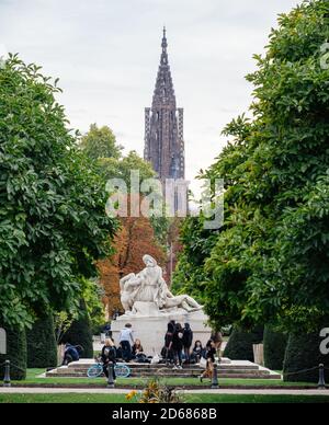 Strasburgo, Francia - 10 ottobre 2020: Giovani adolescenti senza maschere alla statua iconica di fronte al Palais du Rhin con la cattedrale di Notre-Dame sullo sfondo Foto Stock