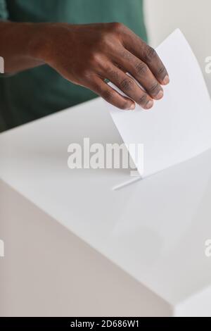 Primo piano di un uomo africano che mette le schede elettorali nelle schede elettorali casella durante l'elezione Foto Stock