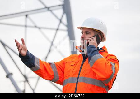 Giovane ingegnere o caposquadra che parla con uno smartphone piattaforma petrolifera o cantiere - fuoco selettivo Foto Stock