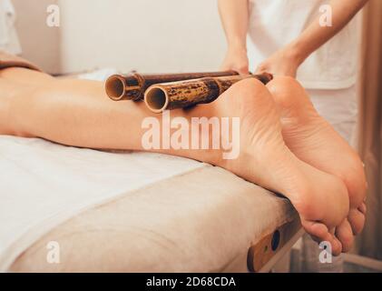 Massaggio alle gambe con bastoncini di bambù. massaggiatore che fa un massaggio tailandese con bastoncini di bambù Foto Stock