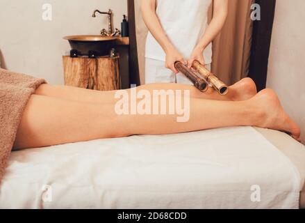 Massaggio alle gambe con bastoncini di bambù. massaggiatore che fa un massaggio tailandese con bastoncini di bambù Foto Stock