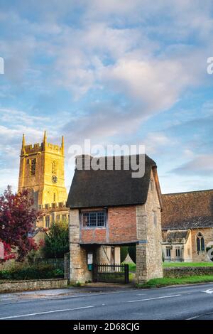 Chiesa di San Pietro e San Paolo e porta di Lych in autunno subito dopo l'alba. Long Compton, Warwickshire, Inghilterra Foto Stock