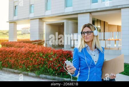 Donna d'affari con cuffie e cellulare Foto Stock