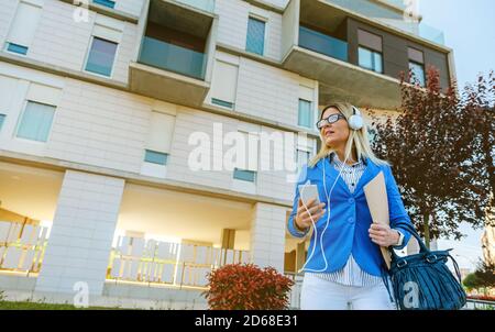 Donna d'affari con cuffie e cellulare Foto Stock