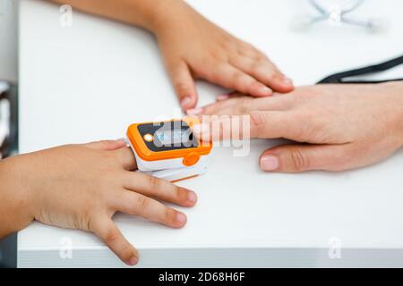 Il pulsossimetro misura la frequenza del polso e l'ossigeno, da vicino al dito del bambino Foto Stock