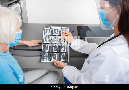 Pulmonologa che mostra ad un paziente anziano una scansione CT dei suoi polmoni. Polmonite, coronavirus, malattie polmonari Foto Stock