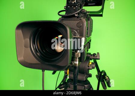 Videocamera TV sullo sfondo di un tasto cromatico verde. Obiettivo della videocamera Foto Stock
