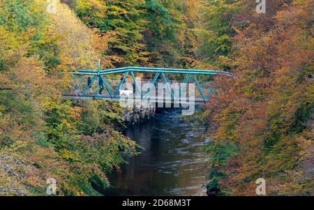 I visitatori ammirano la vista dal ponte pedonale con i colori autunnali sugli alberi che circondano il fiume Garry a Garry Bridge vicino a Killiecrankie, Scozia, Regno Unito Foto Stock