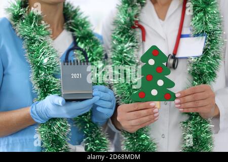 Infermiera con cappotto bianco tenere carta albero di Natale con decorazioni. Foto Stock