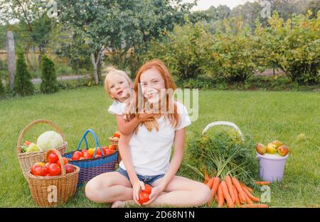 due sorelle che abbracciano un prato verde da una varietà di verdure colorate Foto Stock