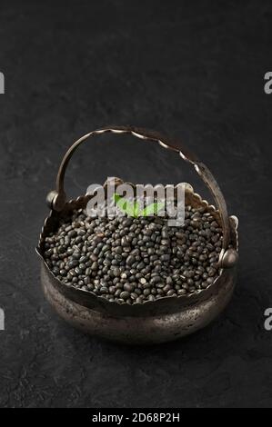 Mucchio di Black Gram o URAD Beans o Mung Beans con foglia verde sulla parte superiore in cesto di ferro su piano di tavolo di ardesia scuro. Vigna Mungo e' popolare cucina indiana Foto Stock