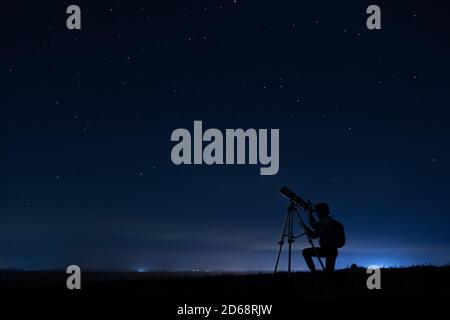 Silhouette umana e telescopio, una donna guarda attraverso un telescopio al cielo stellato. Cielo notturno, stelle, lunga esposizione, astronomia Foto Stock