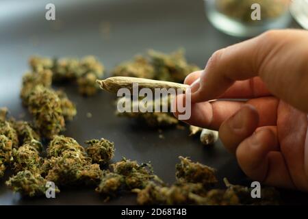 Uomo che tiene in mano la marijuana comune, cannabis su sfondo sfocato con spazio di copia. Fumo erbacce mediche Foto Stock