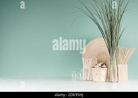 Interni eleganti con decorazione beige naturale in stile ecologico - piante secche, cesto di vimini, piatto di bambù, bouquet di canna, foglia di ramoscelli su menta verde m Foto Stock