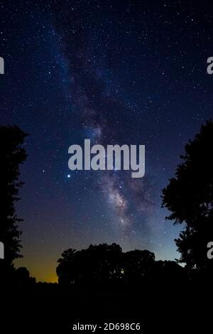 Via Lattea che si estende attraverso il cielo sul paesaggio rurale Foto Stock