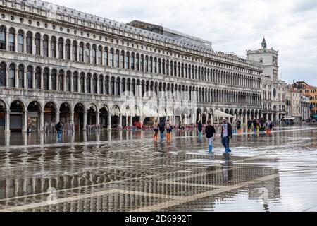 Acque alte - acqua alta che causa inondazioni in Piazza San Marco - turisti che si riversano attraverso l'acqua in abitazioni. Venezia, Italia durante la pandemia di Covid-19. Foto Stock