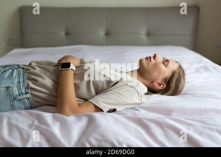 Stanca dopo la notte insonne, giovane donna che si sdraiava e riposava sul divano a casa. Studentessa si rilassa e si addormenta al mattino in soggiorno dopo la festa Foto Stock