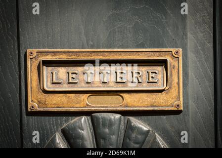 Chiusura di una cassetta di lettere in ottone con testo italiano lettere, porta anteriore in legno in Liguria, Italia, Europa Foto Stock