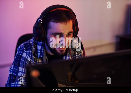 Sorridente durante il processo. Ritratto di giovane giocatore professionista bearded che gioca in un videogioco online Foto Stock