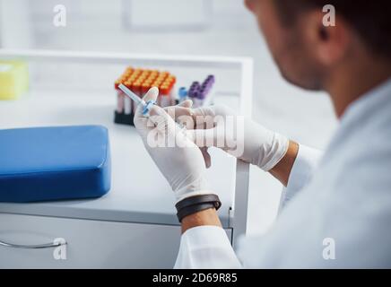 Il medico maschile con siringa si sta preparando per il prelievo di sangue nella sala clinica Foto Stock