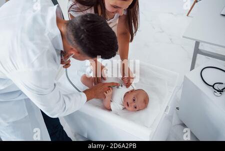 Il pediatra giovane è con il bambino piccolo nella clinica a. giorno Foto Stock