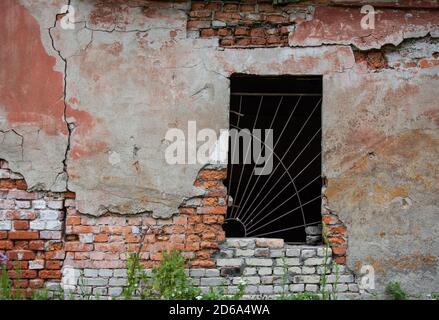 Finestra con griglia in un vecchio muro di mattoni Foto Stock