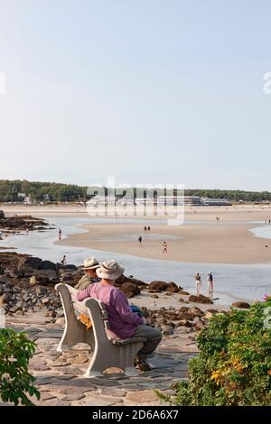 Uomini seduti e parlando su una panchina che si affaccia sulla spiaggia lungo la via marginale a Ogunquit, Maine, Stati Uniti. Foto Stock