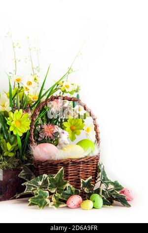 Buona Pasqua. Congratulazioni pasqua background. Uova di Pasqua colorate e fiori con un piccolo coniglietto bianco in cestino. Foto Stock