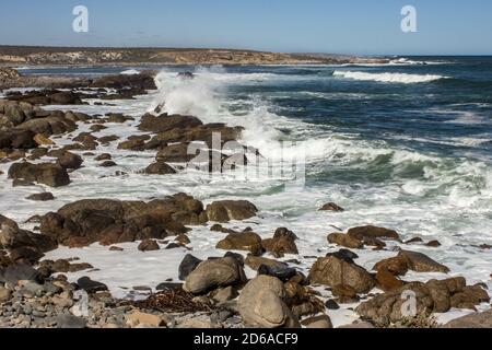 Onde che si infrangono lungo la costa occidentale rocciosa del Sud Africa, fotografate nella sezione costiera del Parco Nazionale di Namaqua in una giornata di sole Foto Stock