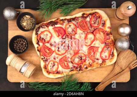 Buon anno e buon Natale, pizza con formaggio, pomodori e pancetta su sfondo marrone. Foto Stock
