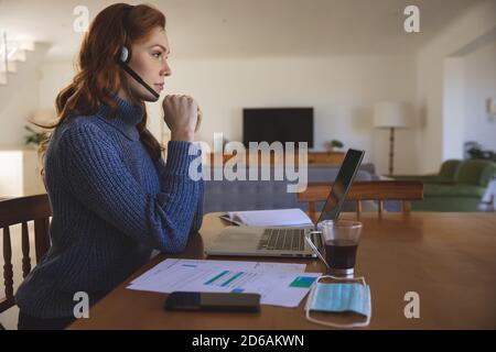 Donna che indossa le cuffie per lavorare a casa Foto Stock