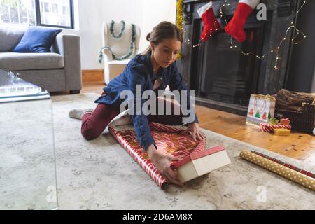 Donna che avvolge regali di Natale a casa Foto Stock