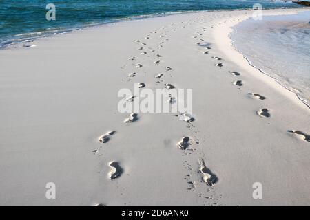 Passi nella sabbia con l'acqua blu dell'oceano e le onde su entrambi i lati Foto Stock