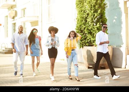 Studenti universitari che camminano insieme all'aperto. Giovani, persone di diverse nazionalità, camminano per la città e parlano. Foto Stock