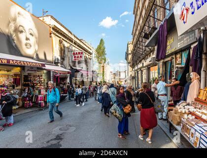 I turchi locali fanno shopping nel grande mercato all'aperto di Eminonu, mentre camminano vicino ad un murale Marilyn Monroe a Istanbul, Turchia Foto Stock