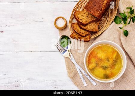 Zuppa di trote con verdure da taglio e pane tostato. Zuppa tradizionale di pesce caldo per uno stile di vita sano. Pannelli di legno bianco sfondo, vista dall'alto Foto Stock