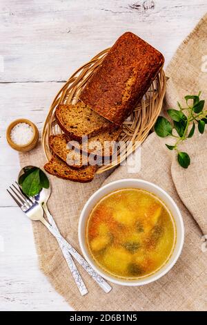 Zuppa di trote con verdure da taglio e pane tostato. Zuppa tradizionale di pesce caldo per uno stile di vita sano. Pannelli di legno bianco sfondo, vista dall'alto Foto Stock