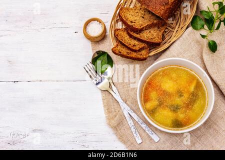 Zuppa di trote con verdure da taglio e pane tostato. Zuppa tradizionale di pesce caldo per uno stile di vita sano. Pannelli di legno bianco sfondo, vista dall'alto Foto Stock