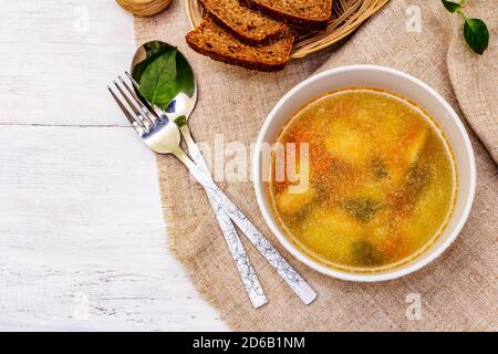 Zuppa di trote con verdure da taglio e pane tostato. Zuppa tradizionale di pesce caldo per uno stile di vita sano. Pannelli di legno bianco sfondo, vista dall'alto Foto Stock