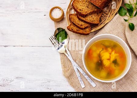 Zuppa di trote con verdure da taglio e pane tostato. Zuppa tradizionale di pesce caldo per uno stile di vita sano. Pannelli di legno bianco sfondo, vista dall'alto Foto Stock