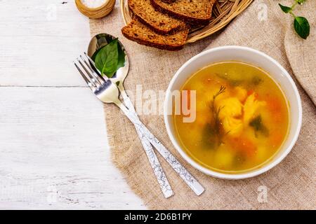 Zuppa di trote con verdure da taglio e pane tostato. Zuppa tradizionale di pesce caldo per uno stile di vita sano. Pannelli di legno bianco sfondo, vista dall'alto Foto Stock