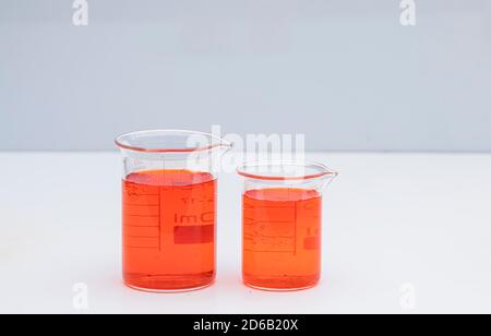 Bicchiere con liquido colorato. Chimica della soluzione. Becher da laboratorio con liquido colorato su sfondo bianco. Foto Stock