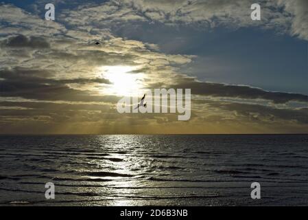 Tramonto sul Mare d'Irlanda come illustrato dalla Blackpool Promenade nel Lancashire, Inghilterra. Due gabbiani possono essere visti volare oltre il sole che tramonta. Foto Stock