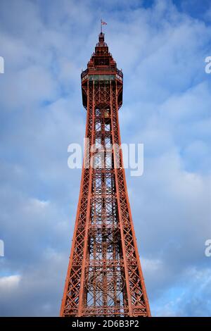 La Blackpool Tower si isolò contro un cielo blu e parzialmente nuvoloso. La torre di colore rosso scuro si distingue per lo sfondo blu pallido e grigio. REGNO UNITO Foto Stock
