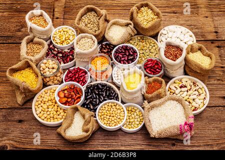 Vari tipi assortiti di fagioli e cereali. Insieme di fonti indispensabili di proteine per uno stile di vita sano. Vecchio tavolo di legno Foto Stock