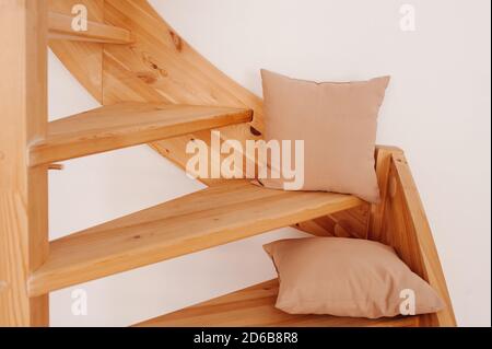 due cuscini beige in tessuto naturale su una scala a chiocciola in legno nella casa. Accogliente arredamento naturale, fuoco selettivo Foto Stock