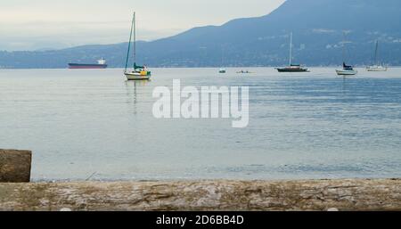 Barche a vela e takers in acqua, montagne dietro Foto Stock