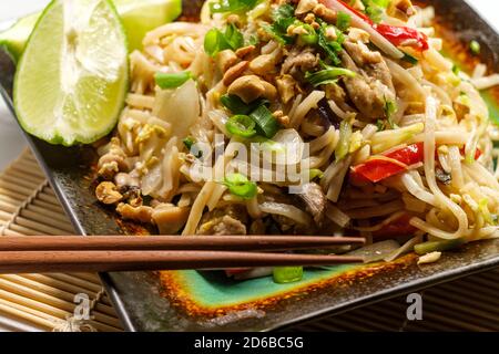 Cucina autentica pad thai con pollo spaghetti di riso peperoni rossi di germogli di soia e la calce e guarnire Foto Stock